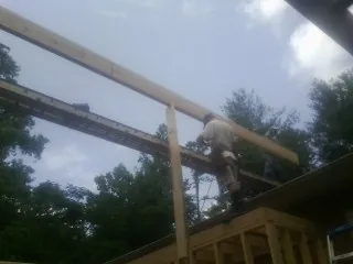 Carpenter setting a ridge beam over a new addition frame — Ice Dam Removal by Roofing Brothers in Washington